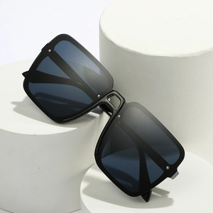 Lunettes de soleil carrées oversize modernes noir mat sur des présentoirs blancs