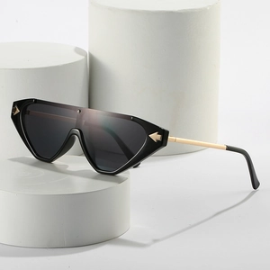 Chic black cat-eye sunglasses with gold arrow accents and metallic temples on a white podium