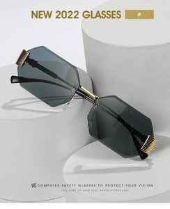 Detail of octagonal rimless sunglasses with dark gray lenses and gold metal temples