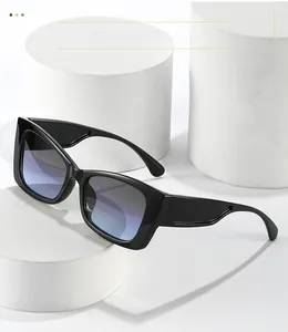 Close-up of black cat-eye sunglasses with blue-purple gradient lenses on a white pedestal