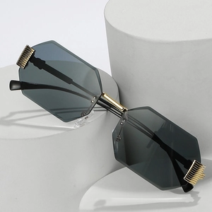 Frameless octagonal sunglasses with dark lenses and gold metal frame on a white pedestal