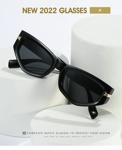 Détail de lunettes œil-de-chat noires avec accents dorés sur un socle blanc épuré
