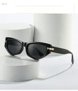 Détail de lunettes de soleil œil-de-chat noires avec charnières dorées sur support