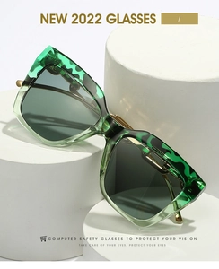Detail of square green tortoiseshell frames with sleek gold metal temples on pedestals