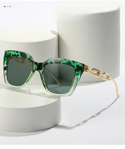 Close-up of leopard print square sunglasses with chunky gold chain temples on white stands