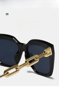 Detail of square sunglasses with thick gold chain temple and black acetate frame