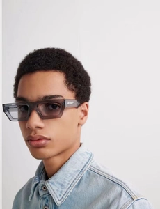Detailansicht der grauen rechteckigen Sonnenbrille mit weißem Logo auf dem Brillenbügel