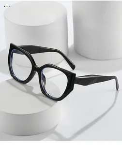 Detail of glossy black cat-eye eyeglass frame displayed on a white cylindrical stand