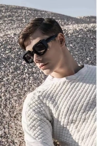 Détail de lunettes de soleil carrées noires à monture épaisse portées par un mannequin
