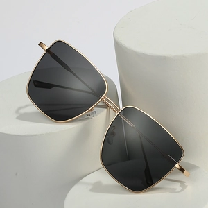 Fashionable square gold metal frame sunglasses with dark lenses on display pedestals