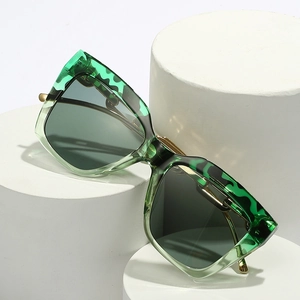 Chic square frame green sunglasses with golden metal temples on white pedestals
