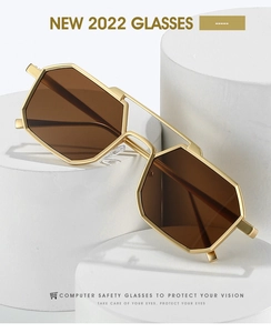Detail of octagonal gold metal frame sunglasses with brown lenses on display base