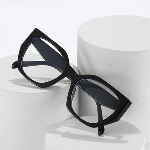 Polished black cat eye eyeglass frames with sharp geometric edges on white pedestals