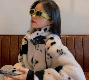 Detail of trendy green thick-frame square sunglasses worn with cow print faux fur coat
