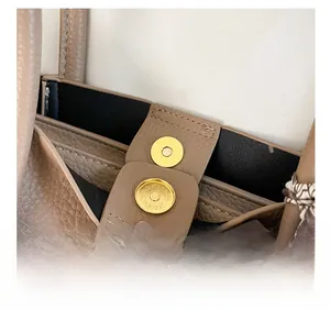 Close-up of pebble grain leather texture with gold magnetic clasp and silk scarf detail