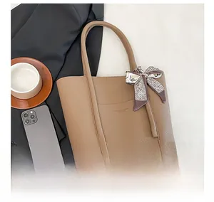 Close-up of khaki pebbled leather tote bag with silk scarf detail and protective base studs