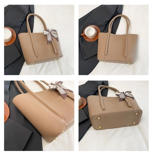 Macro detail of textured leather tote bag with gold hardware and silk scarf wrap