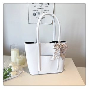 Close-up of white lychee pattern tote bag featuring a silk scarf on the handle