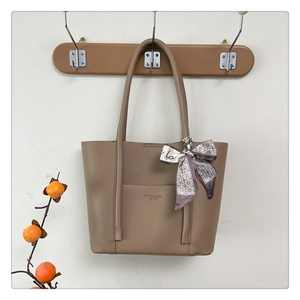 Close-up of brown pebbled leather tote bag with a decorative silk scarf on a wooden hanger