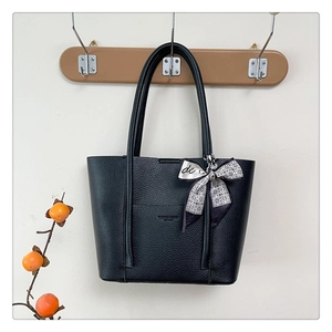 Detail of black lychee grain leather tote bag with a decorative silk scarf on the handle