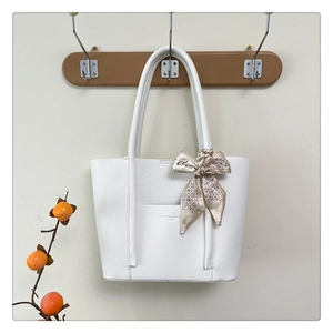 Close-up of white pebble leather tote bag featuring a decorative silk scarf on a wooden hook