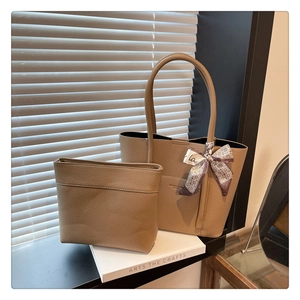 Detail of khaki lychee grain leather tote bag set with decorative silk scarf handle