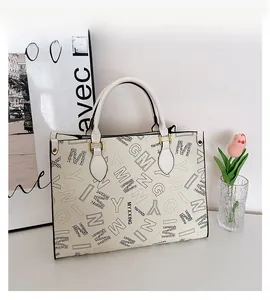 Detail of printed tote bag with metal buckle and decorative side rivets on desk