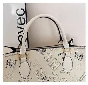 Close-up of cream leather tote bag featuring modern graffiti letter print and gold hardware