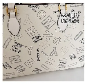 Close-up of premium leather texture with black typography on white tote bag surface