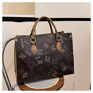 Detail of a large brown tote bag with logo prints and contrast top handles on a chair