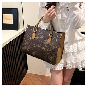 Detailed shot of a large brown tote bag with letter print and gold hardware buckle