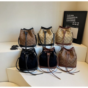 Detail view of woven bucket bags in multiple colors with drawstring closure and slim straps