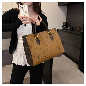 Detailed close-up of large printed tote bag with brown leather handles and letter patterns