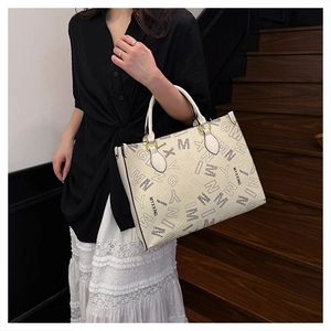 Detail view of large printed tote bag with textured faux leather and golden hardware