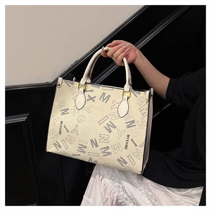 Detailed macro view of the printed alphabet pattern on the cream faux leather tote bag