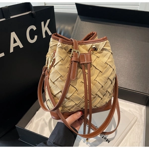Top view of woven bucket bag in khaki and brown leather inside a premium gift box