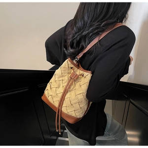 Detail view of woven straw bucket bag featuring leather trim and drawstring closure