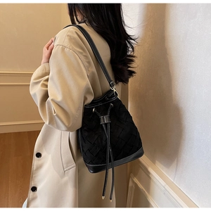 Detail of black woven bucket bag with contrast white stitching and drawstring closure