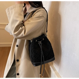 Detail of woven bucket bag with drawstring closure and white contrast stitching accents