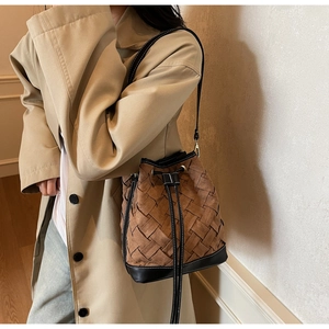 Detail of woven brown and black bucket bag texture on beige trench coat outfit