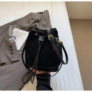 Close-up of black woven leather bucket bag with drawstring closure and gold metal hardware