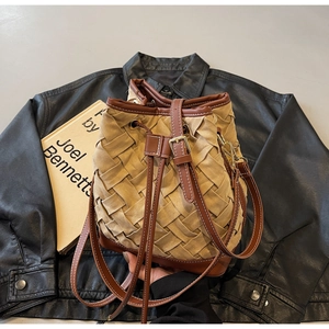 Detail of woven khaki bucket bag with suede texture, drawstring and gold hardware
