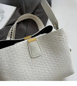 Detail of white woven leather handbag with gold buckle and textured fabric shoulder strap