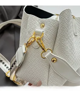 Detail of white woven leather texture with gold metal hardware and geometric strap