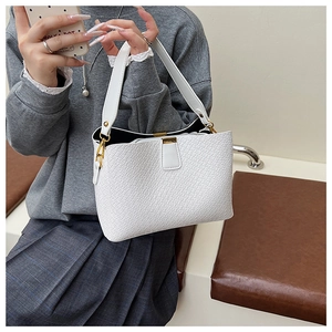 Close-up of white embossed leather handbag with golden lock and strap details