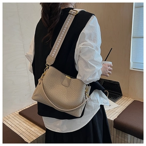 Detail of beige woven PU leather handbag with decorative wide geometric strap and gold hardware