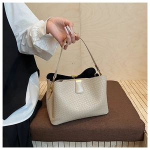 Close-up of beige woven texture handbag with golden metal buckle and top handle