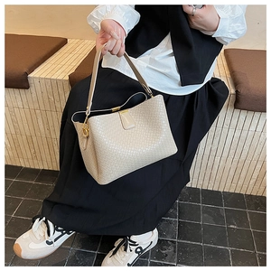 Detailed shot of a beige woven tote bag with magnetic closure and golden hardware