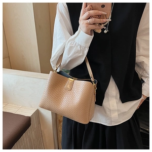 Detailed close-up of beige woven leather texture and golden buckle on bucket handbag