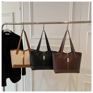 Detail of woven tote bags in beige, black, and brown with golden metal twist lock